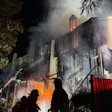 Firefighters battling intense night fire consuming multi-story building with flames and smoke