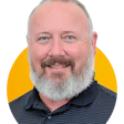 Smiling middle-aged man with gray beard in navy pinstripe polo shirt