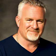 Smiling middle-aged man with gray hair in navy blue V-neck shirt