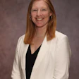 Professional woman smiling, wearing white blazer and black top