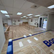 Physical therapy or fitness studio with wooden railings, exercise equipment, and blue-lined wooden floor