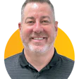 Smiling middle-aged man in striped polo shirt against yellow background