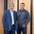 Two professional men in blue and gray business attire standing together