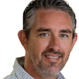 Professional headshot of smiling man in checkered shirt with gray hair
