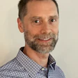Smiling middle-aged man with gray beard in blue checkered shirt