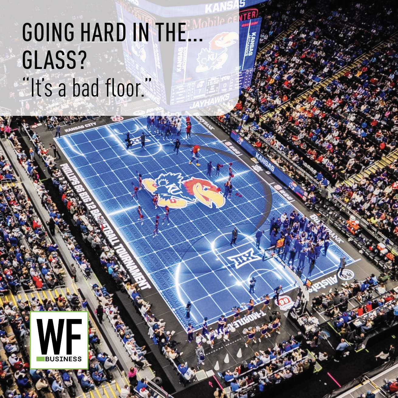 Aerial view of Allen Fieldhouse basketball court with Kansas Jayhawks logo, packed stadium crowd, and blue court floor during game.