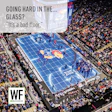 Aerial view of Allen Fieldhouse basketball court with Kansas Jayhawks logo, packed stadium crowd, and blue court floor during game.