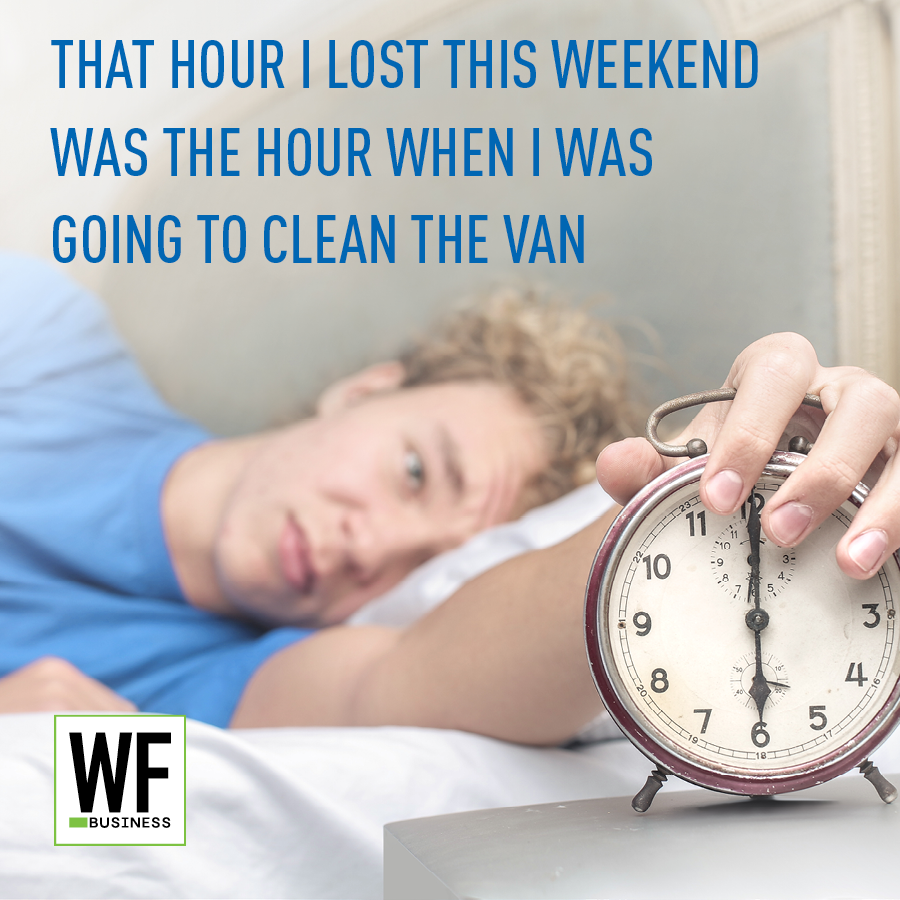 Person sleeping in bed with alarm clock showing daylight saving time, captioned about lost cleaning time