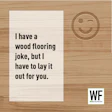 Humorous wood flooring joke with winking smiley face and WE Business branding on wooden background