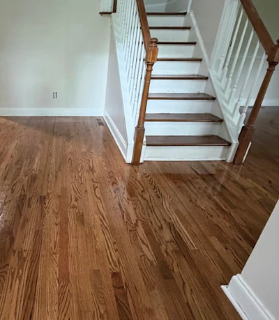 In this foyer, the stair treads were refinished to match the field and the risers painted so the floor and stairs read as one continuous surface.