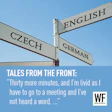 Multilingual street signs showing Czech, German, and English directions with a quote about meeting delays and WE Business branding