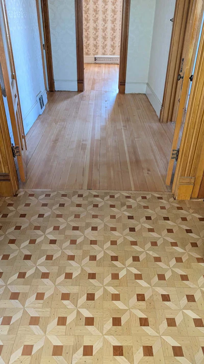 Elegant hallway with ornate geometric parquet flooring and wooden doorways