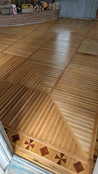 Garage floor with geometric wood parquet pattern featuring herringbone and star designs in varying wood tones
