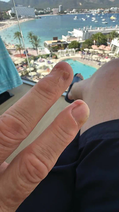 Hand pointing toward coastal resort with marina, pools, and beachfront buildings below