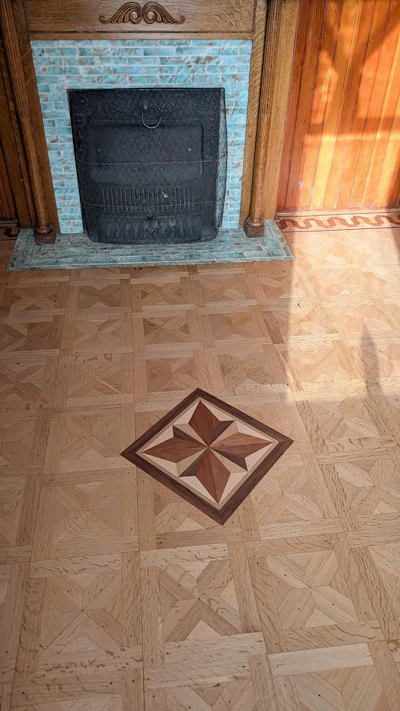 Elegant fireplace with light blue brick surround and decorative parquet floor featuring a geometric star pattern inlay