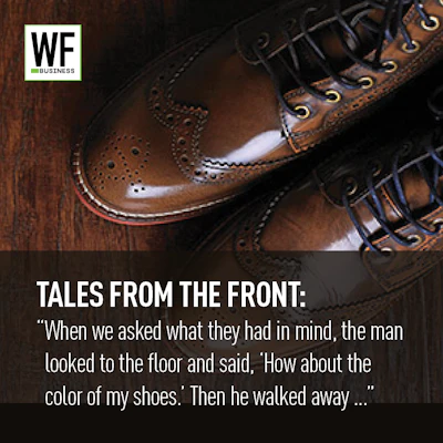 Polished brown leather dress shoes with decorative stitching displayed on wooden surface