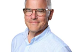 Professional headshot of middle-aged man wearing light blue pinstriped shirt and glasses
