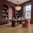 Modern burgundy office with arched shelving, wooden desk, pink velvet chair, glass chandelier, and city views