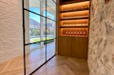 Modern entryway with black-framed glass doors, white brick walls, chevron flooring, and illuminated wooden wine display cabinet