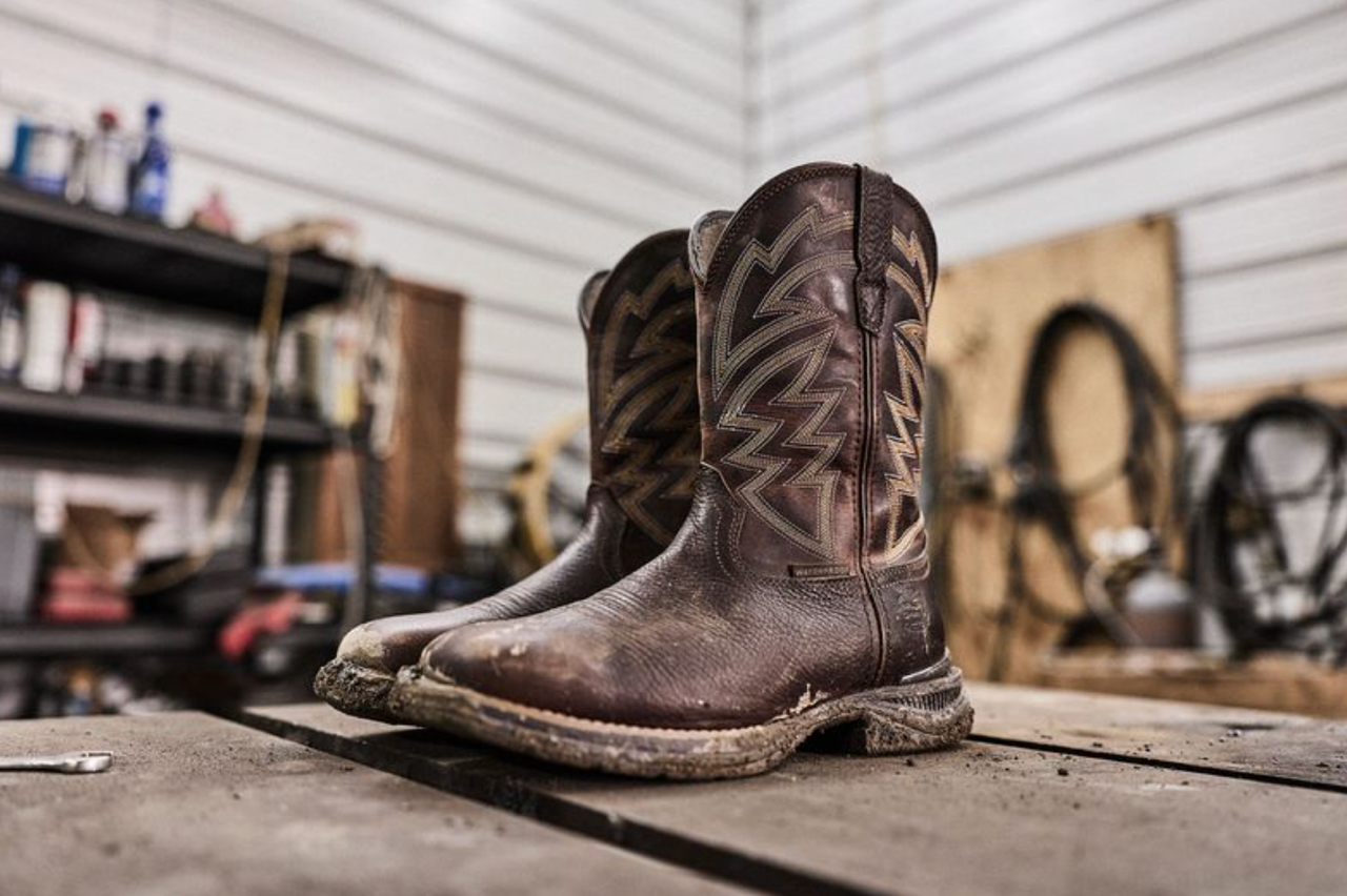 Worn brown cowboy boots displayed on concrete floor in a garage workshop setting