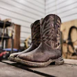 Worn brown cowboy boots displayed on concrete floor in a garage workshop setting