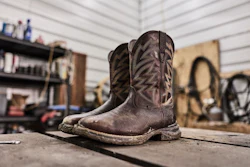 Worn brown cowboy boots displayed on concrete floor in a garage workshop setting