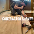 Wood flooring contractor kneeling while installing hardwood flooring with power tools on a residential floor
