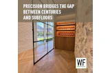 Modern interior hallway with glass doors, wooden chevron flooring, stone walls, and illuminated wine display cabinet