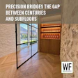 Modern interior hallway with glass doors, wooden chevron flooring, stone walls, and illuminated wine display cabinet
