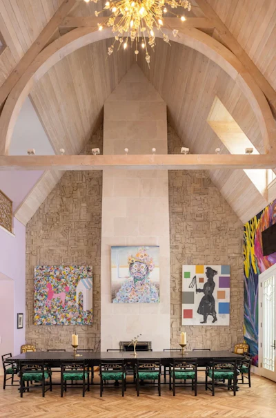 Modern gallery space with vaulted ceiling, long black dining table, and contemporary artwork displayed on textured walls