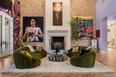Modern living room with green curved armchairs, fireplace, and contemporary art on textured brick walls