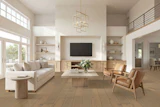 Modern open-concept living room with neutral furnishings, wood flooring, wall-mounted TV, and abundant natural light from large windows