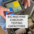 Technician testing capacitors inside industrial machine control panel during maintenance checkup