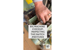 Technician inspecting electrical switches and fuses inside industrial machinery during maintenance checkup