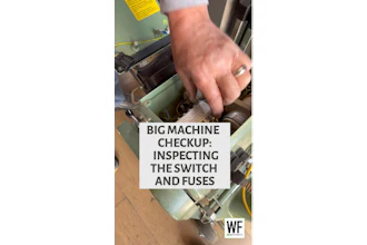 Technician inspecting electrical switches and fuses inside industrial machinery during maintenance checkup